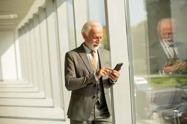 Starszy Biznesmen Stoi Biurze Skupiony Telefonie Komórkowym Jest Ubrany Strój Obrazek Stockowy