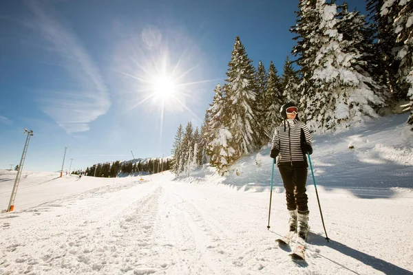 1人の若い女性がスキーブーツとサングラスで完全な雪のギアを身に着けているスキーの晴れた冬の日を楽しんでいます — ストック写真