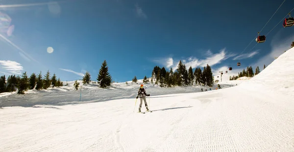 1人の女の子はスキーブーツとサングラスで完全な雪のギアを身に着けているスキーの晴れた冬の日を楽しんでいます — ストック写真