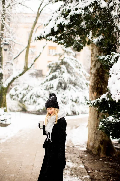 一个年轻的女人站在一个冬日的仙境里 穿着暖和的衣服 喝着热咖啡去了 — 图库照片