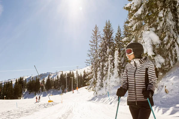 雪に覆われた斜面で冬のスキーを楽しむ若い女性 背の高い木に囲まれ 寒さのために身を包んだ — ストック写真
