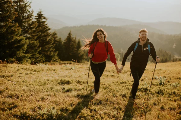 Sırt Çantaları Yeşil Tepelerde Yürüyen Gülümseyen Genç Çift — Stok fotoğraf