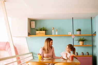Anne ve kızı kahvaltıda kafede taze sıkılmış meyve sularıyla iyi vakit geçiriyorlar.
