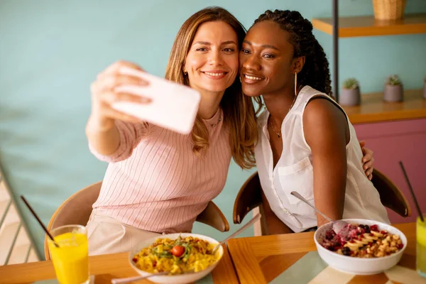Две Симпатичные Девушки Белая Черная Делают Селфи Мобильным Телефоном Кафе — стоковое фото