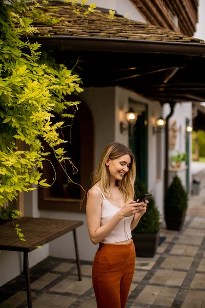 Красивая Молодая Женщина Стоит Заднем Дворе Пользуется Мобильным Телефоном — стоковое фото