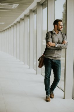 Yakışıklı genç ve modern iş adamı ofis koridorunda duruyor.