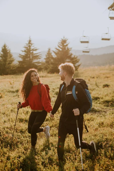 Uśmiechnięta Młoda Para Spacerująca Plecakami Zielonych Wzgórzach — Zdjęcie stockowe