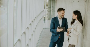 Ofis koridorunda dijital tablet kullanan yakışıklı ve modern iş adamları.