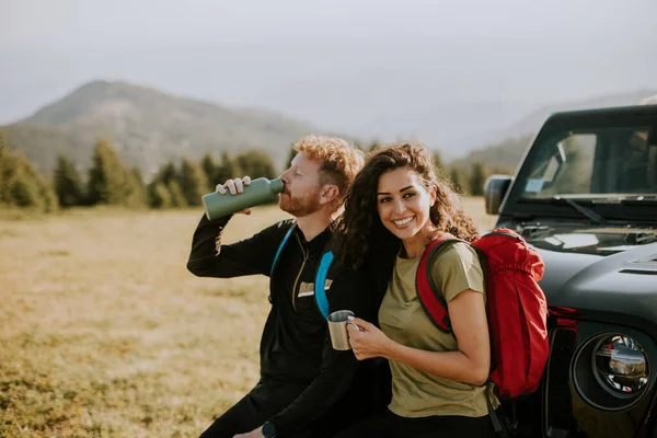 Smiling Young Couple Preparing Hiking Adventure Backpacks Terrain Vehicle — Stockfoto