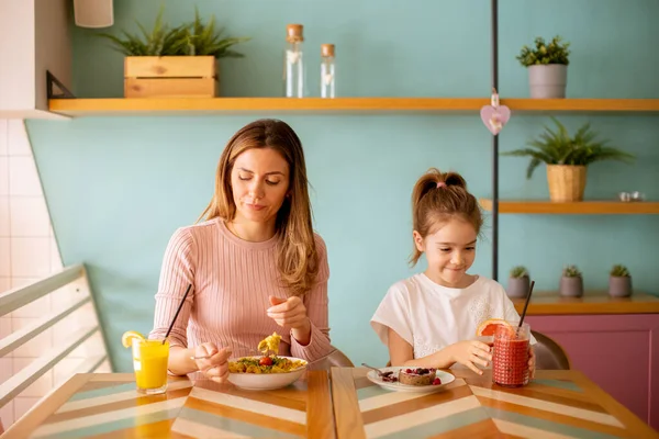 母亲和女儿在早餐时用新鲜的榨汁在咖啡馆里度过了一段愉快的时光 — 图库照片