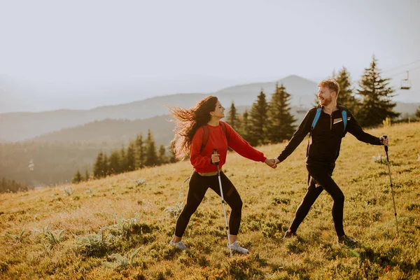 Uśmiechnięta Młoda Para Spacerująca Plecakiem Zielonych Wzgórzach — Zdjęcie stockowe