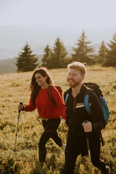 Sırt Çantalı Yeşil Tepelerde Yürüyen Gülümseyen Genç Çift — Stok fotoğraf