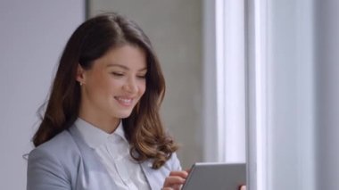 Ofis koridorunda dijital tablet üzerinde çalışan güzel genç bir kadın.