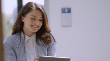 Ofis koridorunda dijital tablet üzerinde çalışan güzel genç bir kadın.