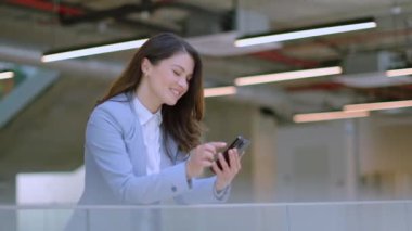 Ofis koridorunda cep telefonu kullanan genç ve güzel bir iş kadını.