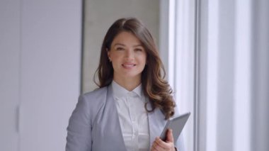 Ofis koridorunda dijital tablet üzerinde çalışan güzel genç bir kadın.