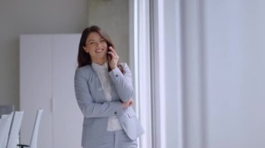 Ofis koridorunda cep telefonu kullanan genç ve güzel bir iş kadını.