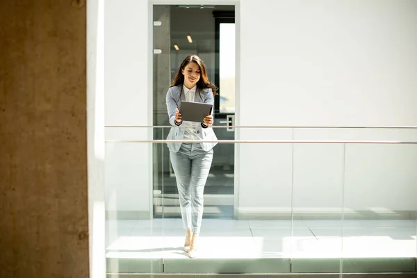 Ofis Koridorunda Dijital Tablet Üzerinde Çalışan Güzel Genç Bir Kadın — Stok fotoğraf