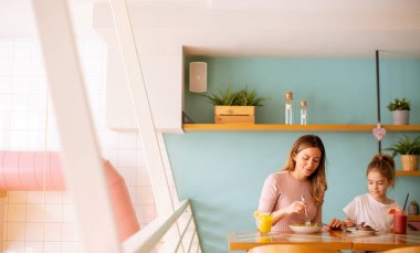 Anne ve kızı kahvaltıda kafede taze sıkılmış meyve sularıyla iyi vakit geçiriyorlar.
