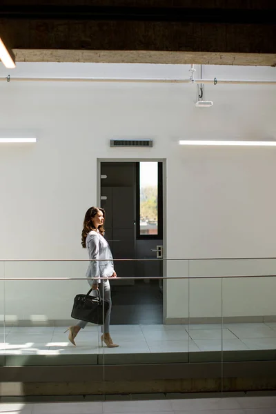 オフィスの廊下でブリーフケースを持って歩くかなり若いビジネス女性 — ストック写真