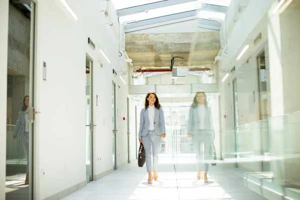 オフィスの廊下でブリーフケースと一緒に歩くかなり若いビジネス女性 — ストック写真