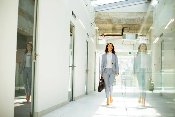 オフィスの廊下でブリーフケースと一緒に歩くかなり若いビジネス女性 — ストック写真