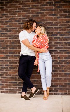 Evdeki tuğla duvarın önünde birbirine aşık genç ve güzel bir çift.