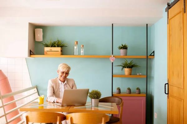 Donna Anziana Che Utilizza Telefono Cellulare Mentre Lavora Sul Computer — Foto Stock