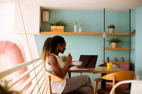 若い黒人女性は カフェでラップトップで作業しながら 健康的な朝食を持っています — ストック写真