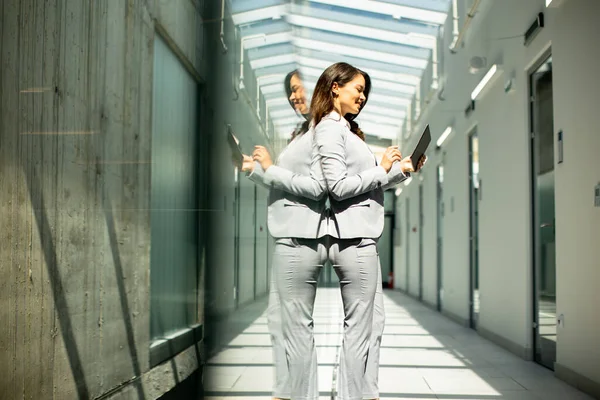 stock image Pretty young woman working on digital tablet in the office hallway