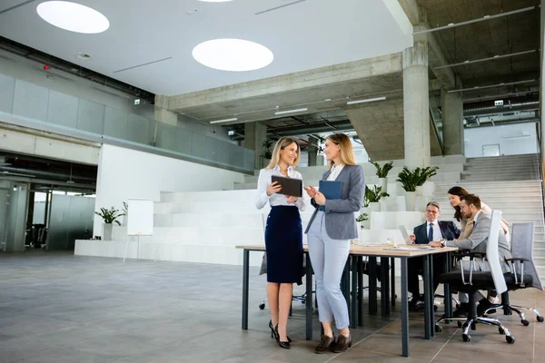 两名漂亮的年轻女商人站在办公室的团队面前 看着数字平板电脑上的财务业绩 — 图库照片