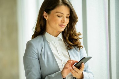 Ofis penceresinin yanında cep telefonu kullanan güzel bir bayan.