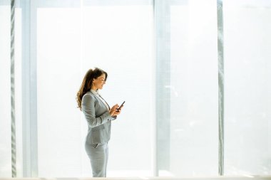 Ofis penceresinin yanında cep telefonu kullanan güzel bir bayan.