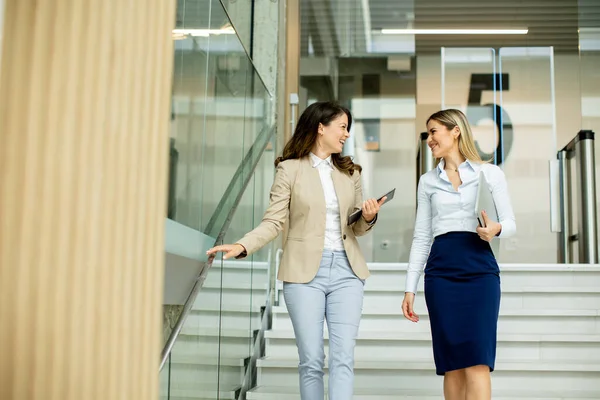2人のかわいい若いビジネスマンの女性がオフィスの廊下を歩いている — ストック写真