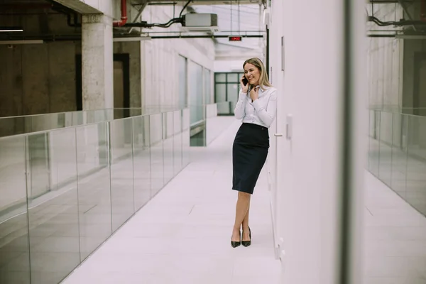 オフィスの廊下で携帯電話を使用してかなり若いビジネス女性 — ストック写真