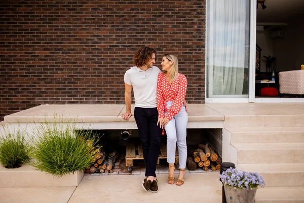 stock image Handsome ymiling young couple in love sitting in front of house brick wall