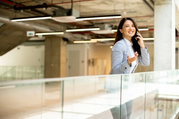 オフィスの廊下で携帯電話を使用してかなり若いビジネス女性 — ストック写真