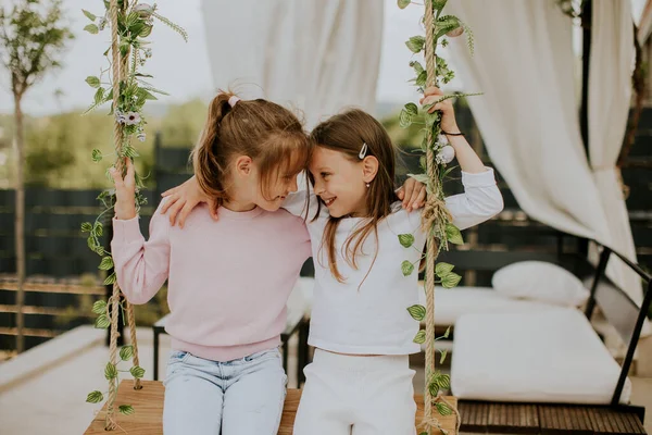 stock image Two cute little girls on the swing in the house backyard