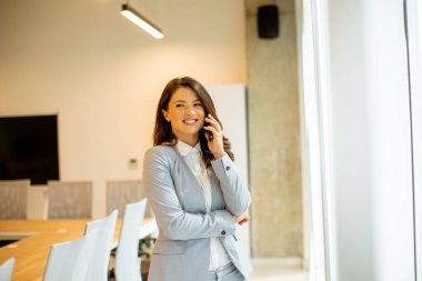 Ofis penceresinin yanında cep telefonu kullanan güzel bir bayan.