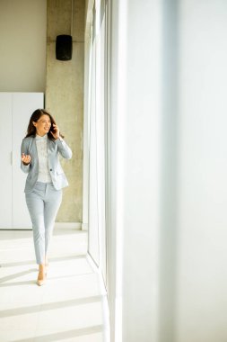 Ofis penceresinin yanında cep telefonu kullanan güzel bir bayan.