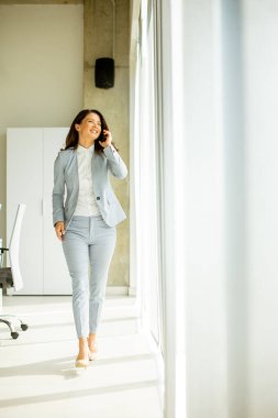 Ofis penceresinin yanında cep telefonu kullanan güzel bir bayan.