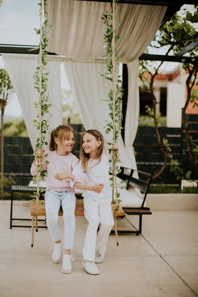 stock image Two cute little girls on the swing in the house backyard