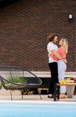 Evin arka bahçesinde yüzme havuzunda dinlenen yakışıklı genç bir çift.
