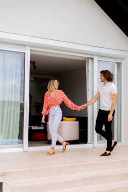 Güzel, gülümseyen, birbirine aşık genç bir çift evin önünde yürüyor.