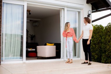 Güzel, gülümseyen, birbirine aşık genç bir çift evin önünde yürüyor.