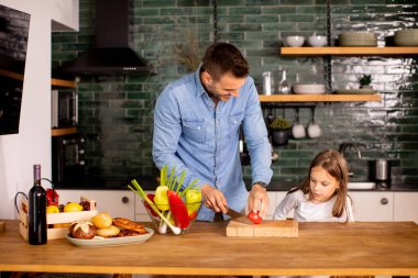 Mutlu baba ve kız mutfakta sebze hazırlıyor.