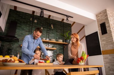 Genç ve mutlu bir aile mutfakta sebze hazırlıyor.