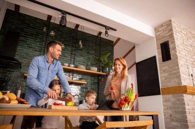 Genç ve mutlu bir aile mutfakta sebze hazırlıyor.
