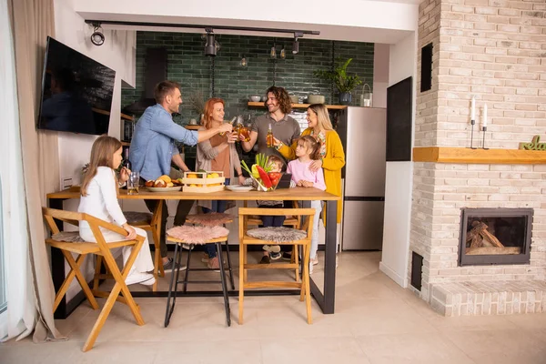 两个快乐的家庭在厨房准备晚餐的时候用苹果酒祝酒 — 图库照片