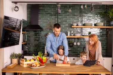 Genç ve mutlu bir aile mutfakta sebze hazırlıyor.